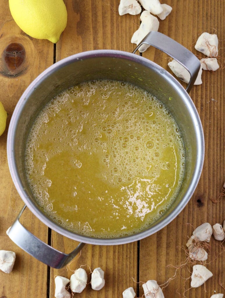 Eggs and sugar cooking in a pot with lemon zest
